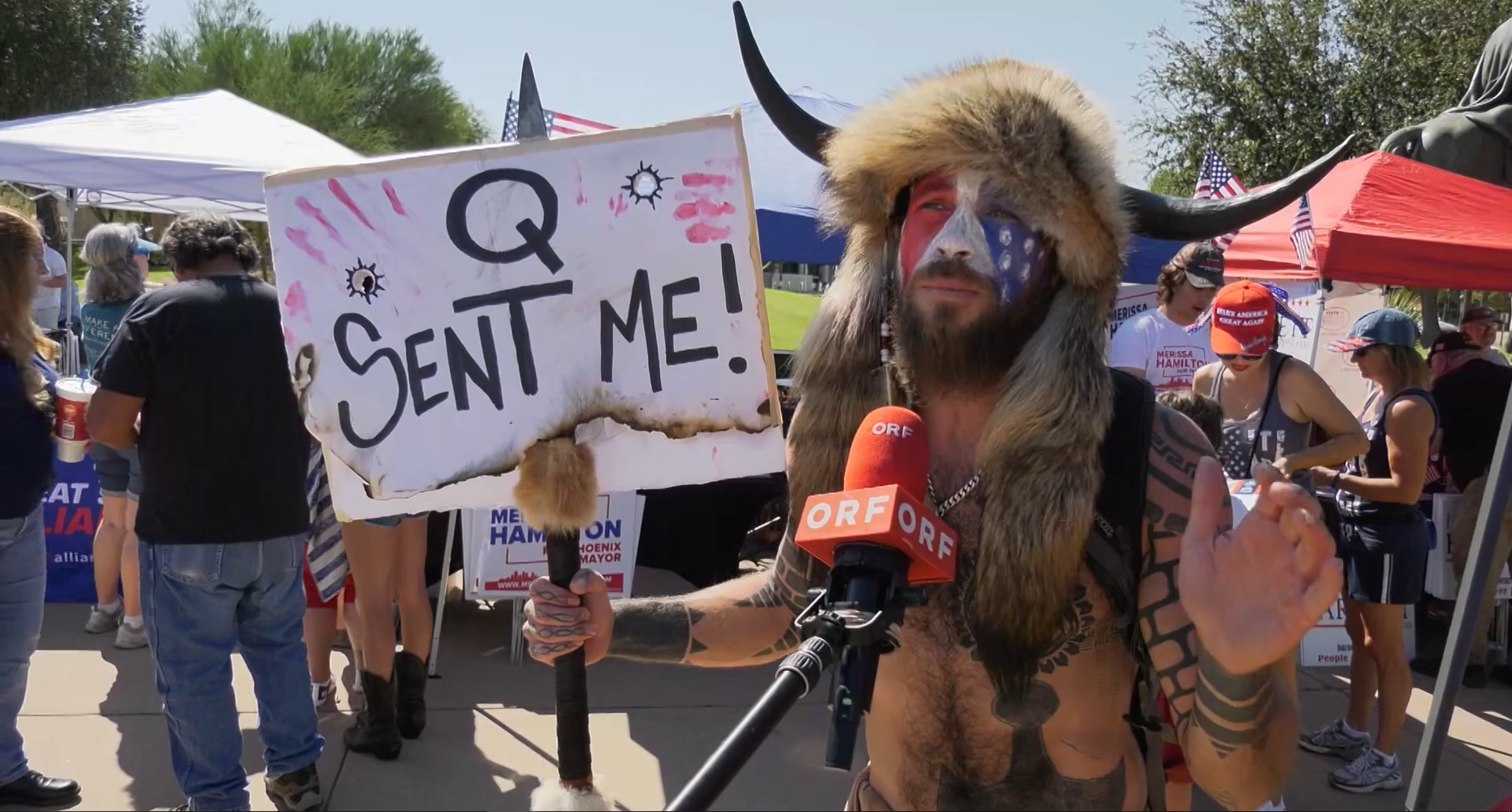 Jake Angeli, uno de los fanáticos de Trump que irrumpió en el capitolio el 6 de enero, participaba activamente de protestas a las que asistía con un cartel con la leyenda “Q me envió” y repetía consignas relacionadas a la conspiración a los asistentes (YouTube).